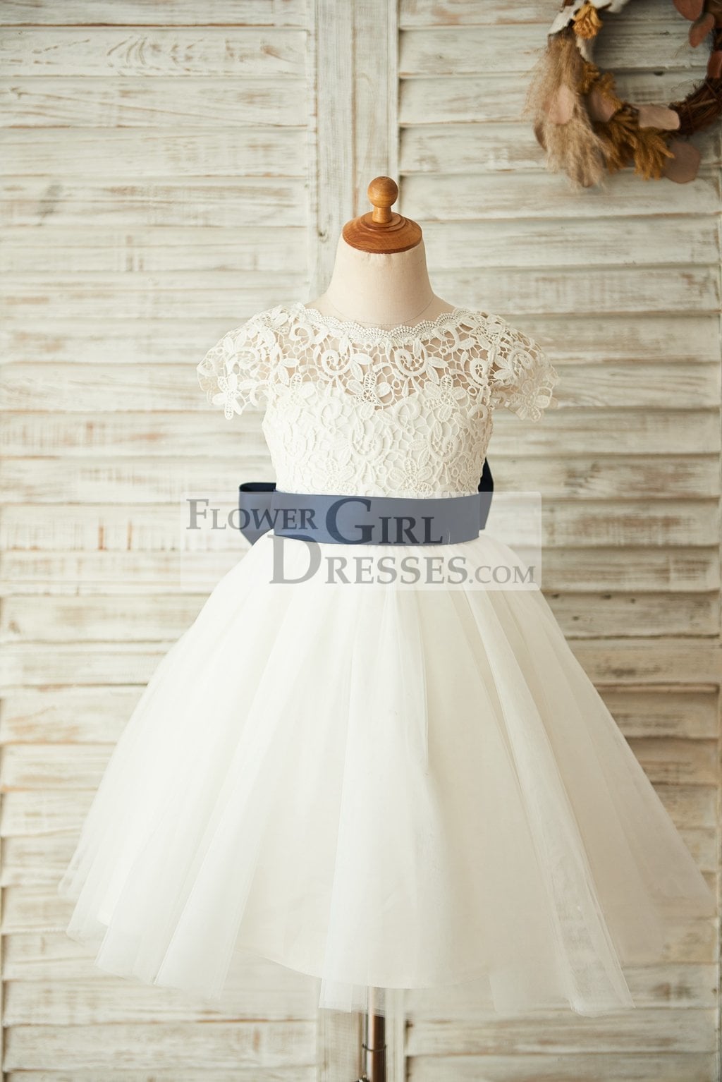 White flower girl dress shop with navy blue sash